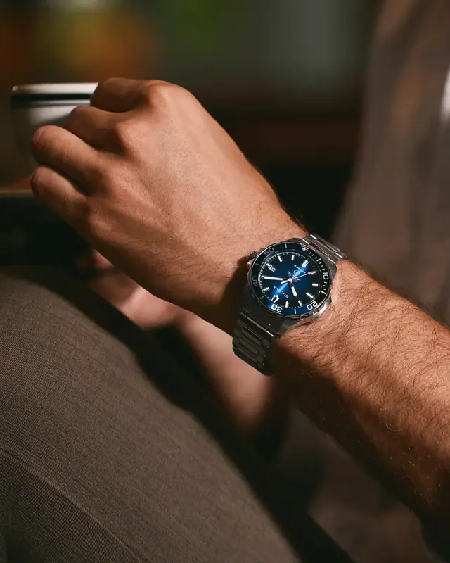 Reloj Bulova Marine Star automático de acero con esfera azul en la muñeca de un hombre