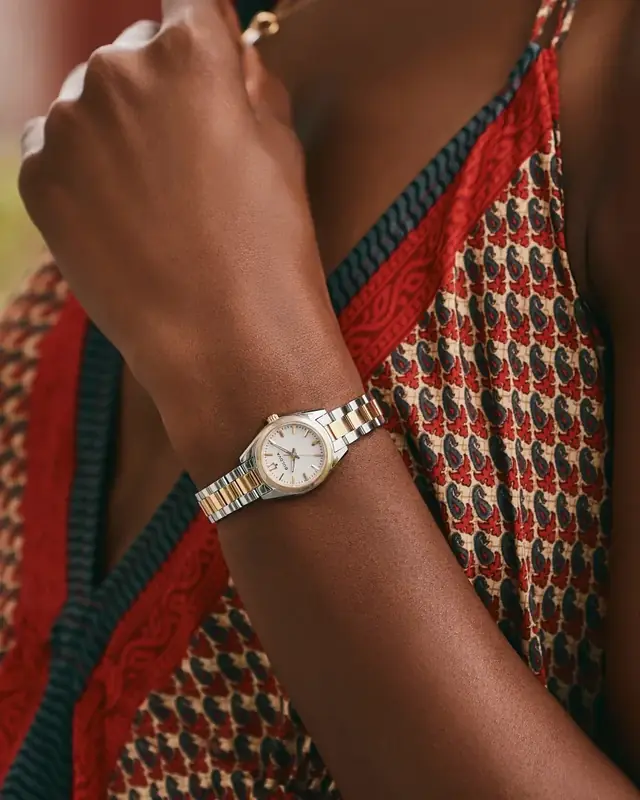 Reloj Bulova bicolor, plateado y color oro, con esfera blanca en la muñeca de una mujer